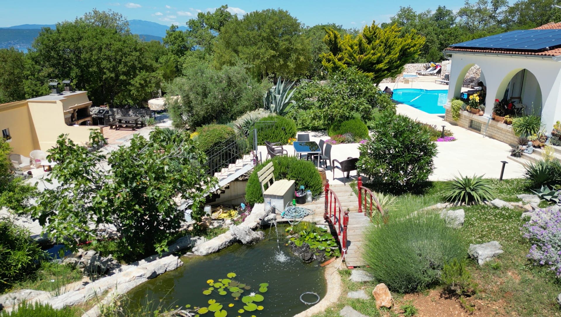 Aerial view over the resort gardens, pond and pool above the Adriatic